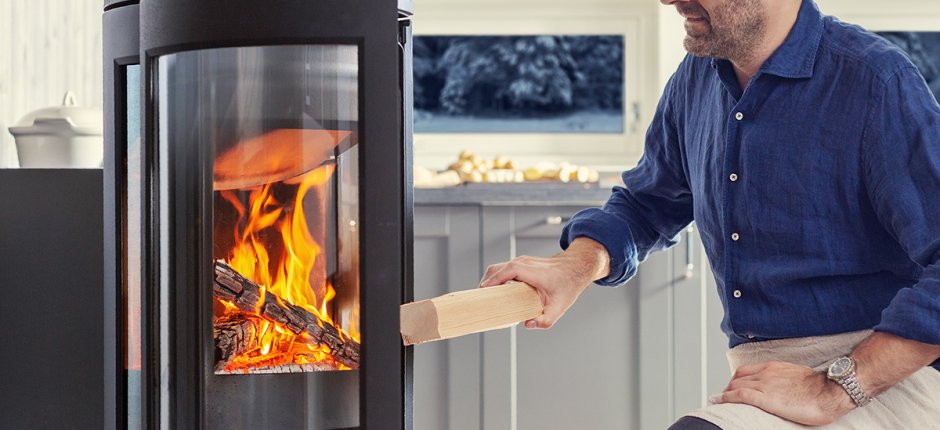 Man put wood in fireplace. Photo.