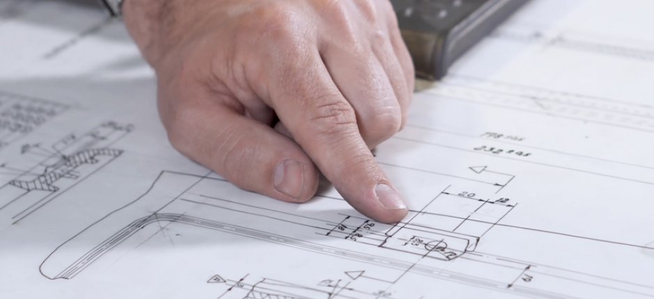 Wskazując ręką na rysunki kominka Jøtul