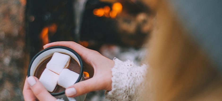 Dziewczyna pije czekoladę przy kominku