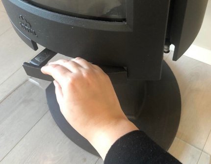 Ręka, która ostrożnie otwiera drzwi pieca na drewno
