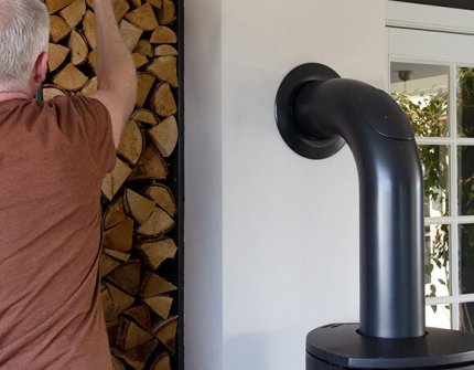 Mężczyzna sięga po drewno do kominka