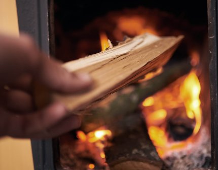 Dokładanie drewna do paslącego się kominka