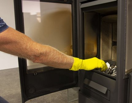 Ręka w żółtej rękawicy czyści kominek