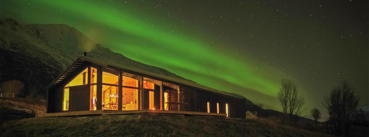 Dom Gapahuk pod niebem rozświetlonym zorzą polarną.