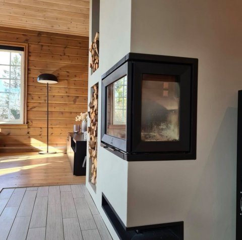 Biała obudowa z wkładem kominkowym o nazwie Jøtul I 520 FR w norweskim domu wakacyjnym.
